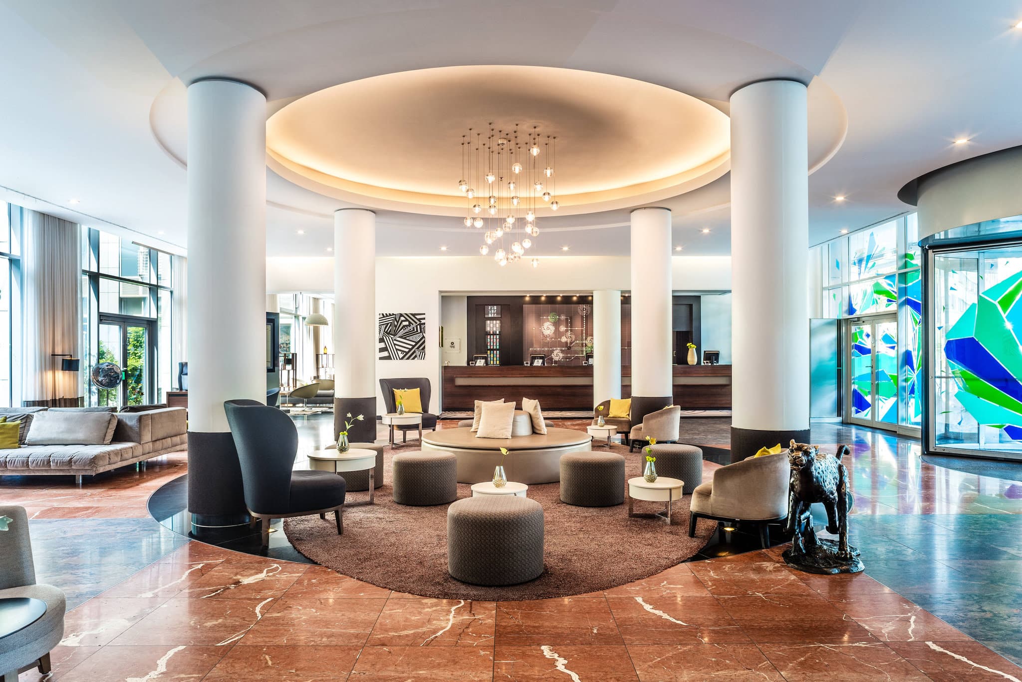 A serene 15-meter indoor hotel pool at Le Méridien Munich with blue tiling and lounge chairs, contrasting with the busy city outside.