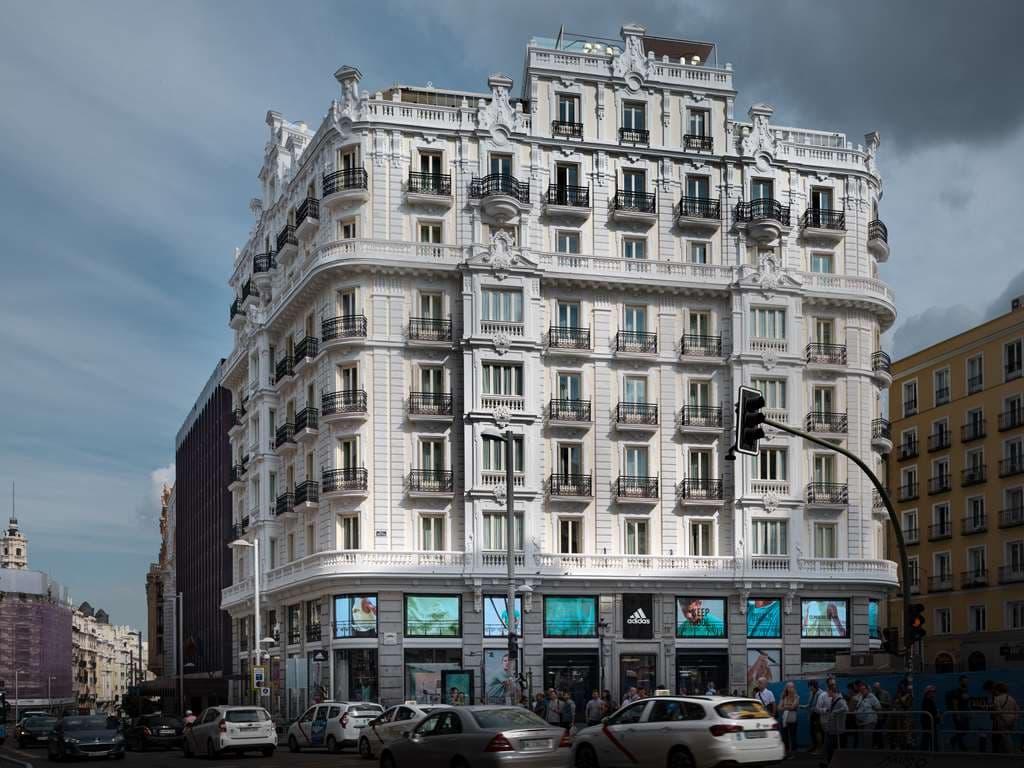 Guests enjoying cocktails at Picalagartos Sky Bar with the iconic Metropolis building and Gran Vía skyline in the background.