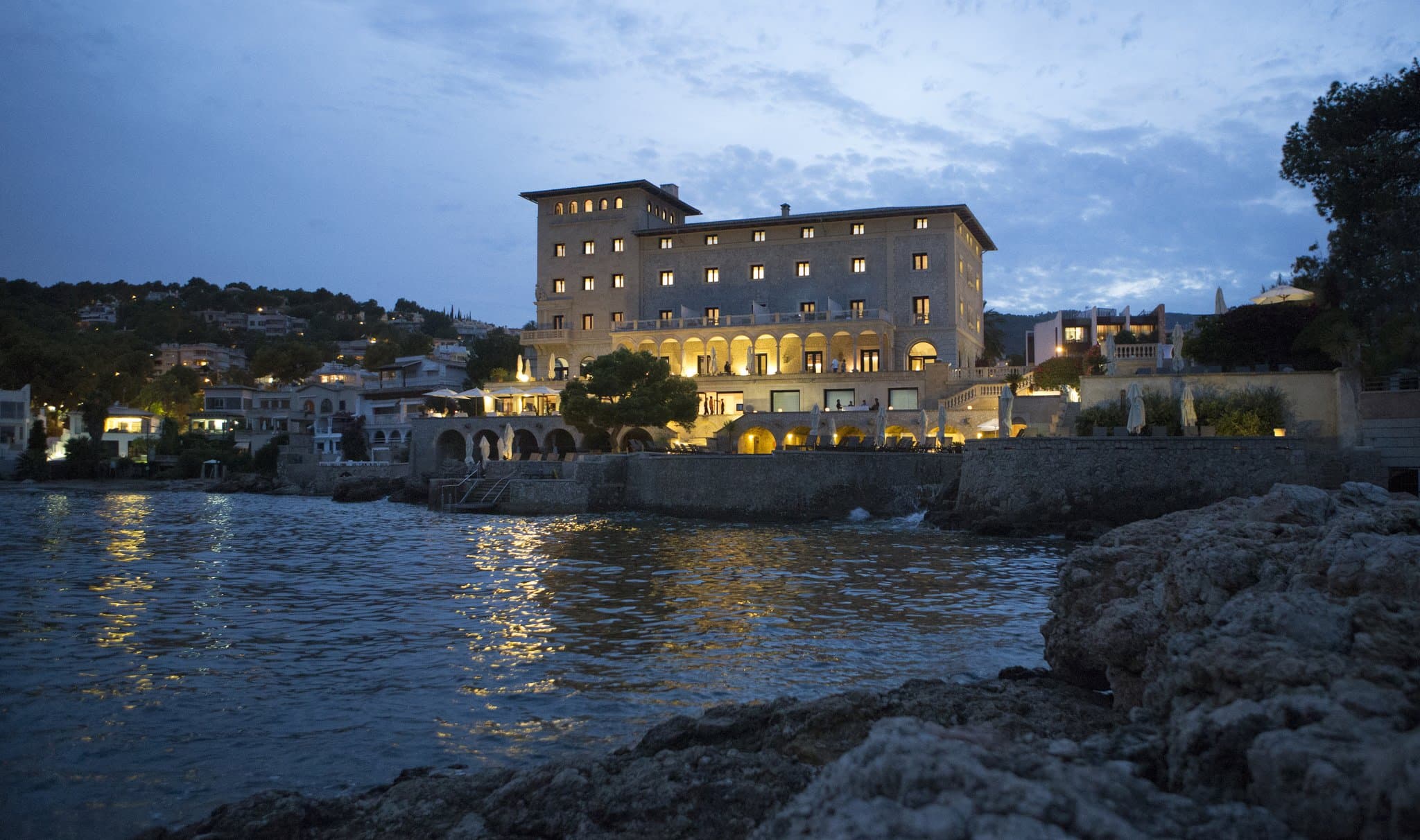 Iconic stone arches of Hospes Maricel framing the Mediterranean Sea with an infinity pool in the foreground.