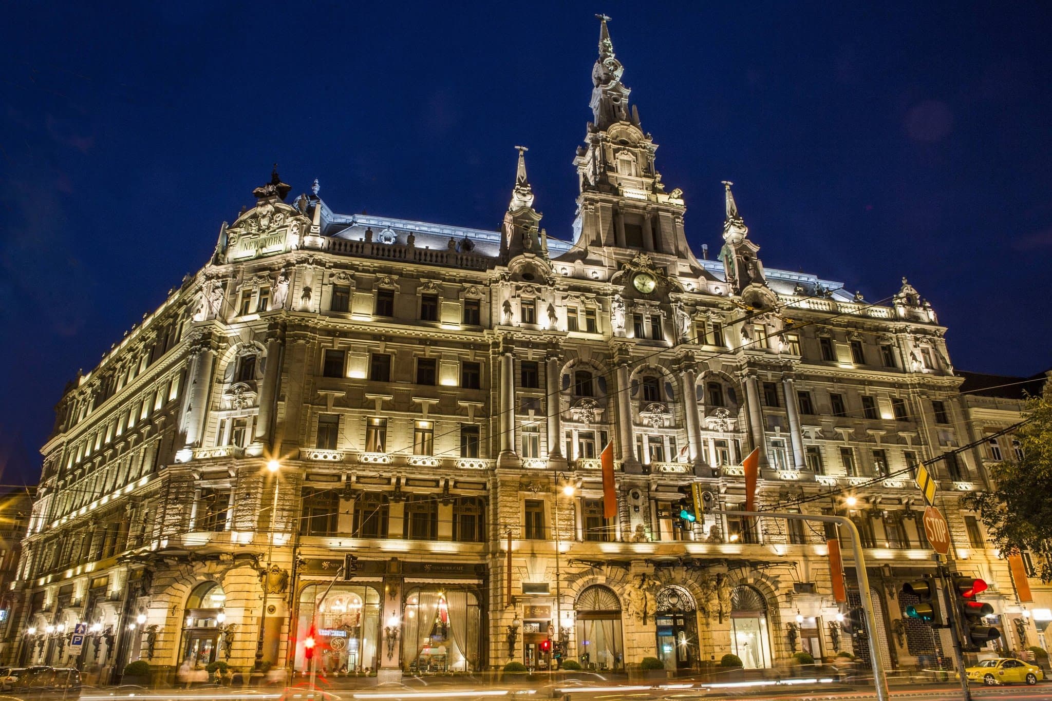 The glass-roofed atrium of the Anantara New York Palace Budapest featuring marble columns and the entrance to the New York Café.