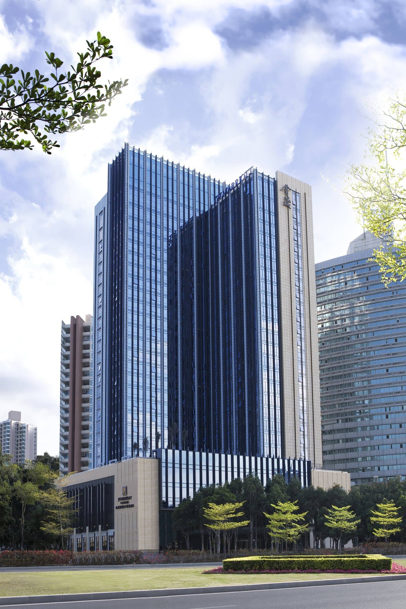 A guest room with floor-to-ceiling windows overlooking the lush green expanse of the Shenzhen Golf Club at sunset.