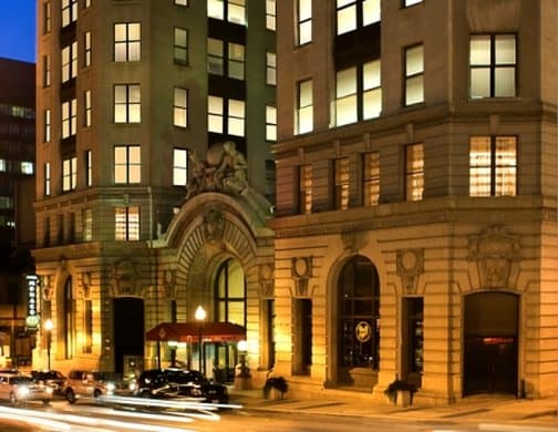 Grand marble staircase of the Kimpton Hotel Monaco Baltimore with stained glass skylight and ornate Beaux-Arts detailing.