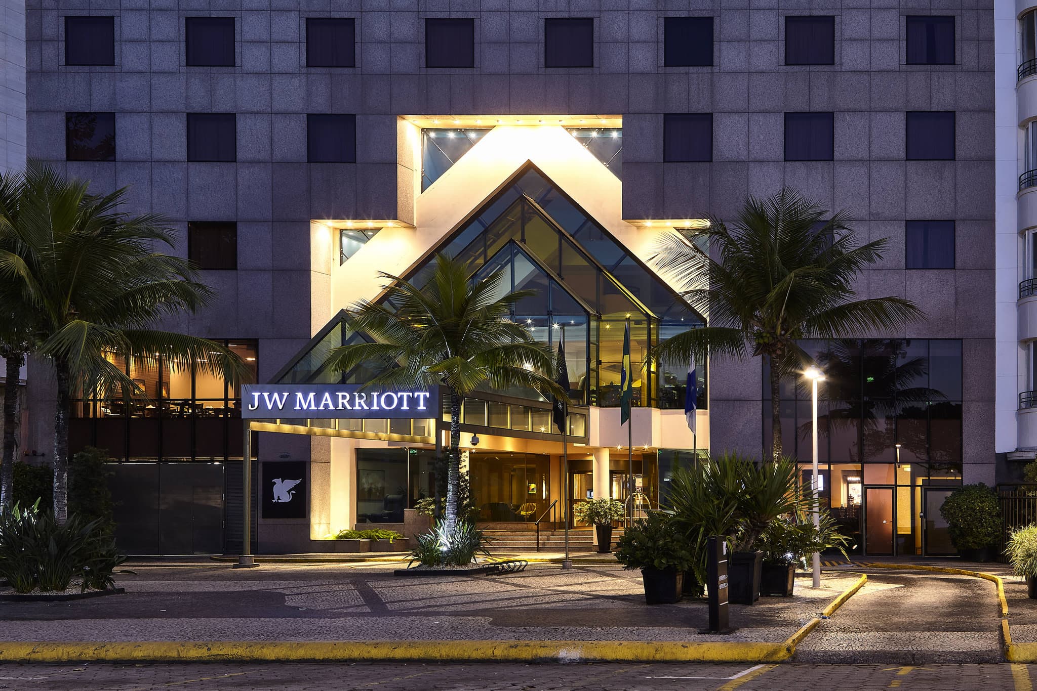 Rooftop pool deck at JW Marriott Rio with guests enjoying cocktails, overlooking Copacabana beach and Sugarloaf Mountain.