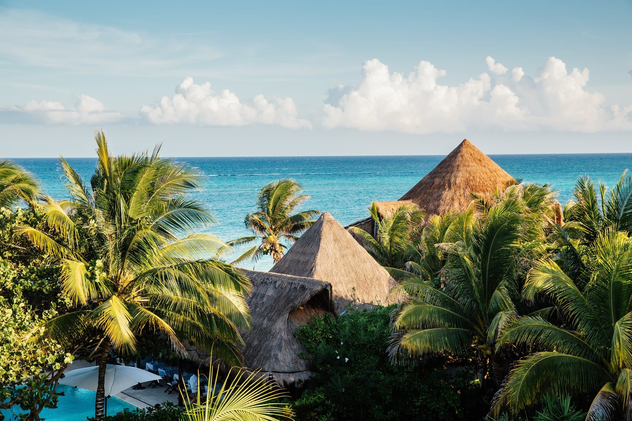 The main house, Casa Grande, framed by palm trees with its iconic white facade and turquoise pool.