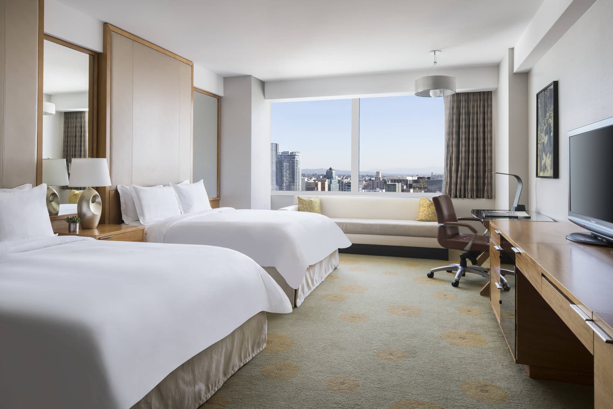 Ritz-Carlton Los Angeles rooftop pool deck with white cabanas and panoramic downtown skyline views at sunset