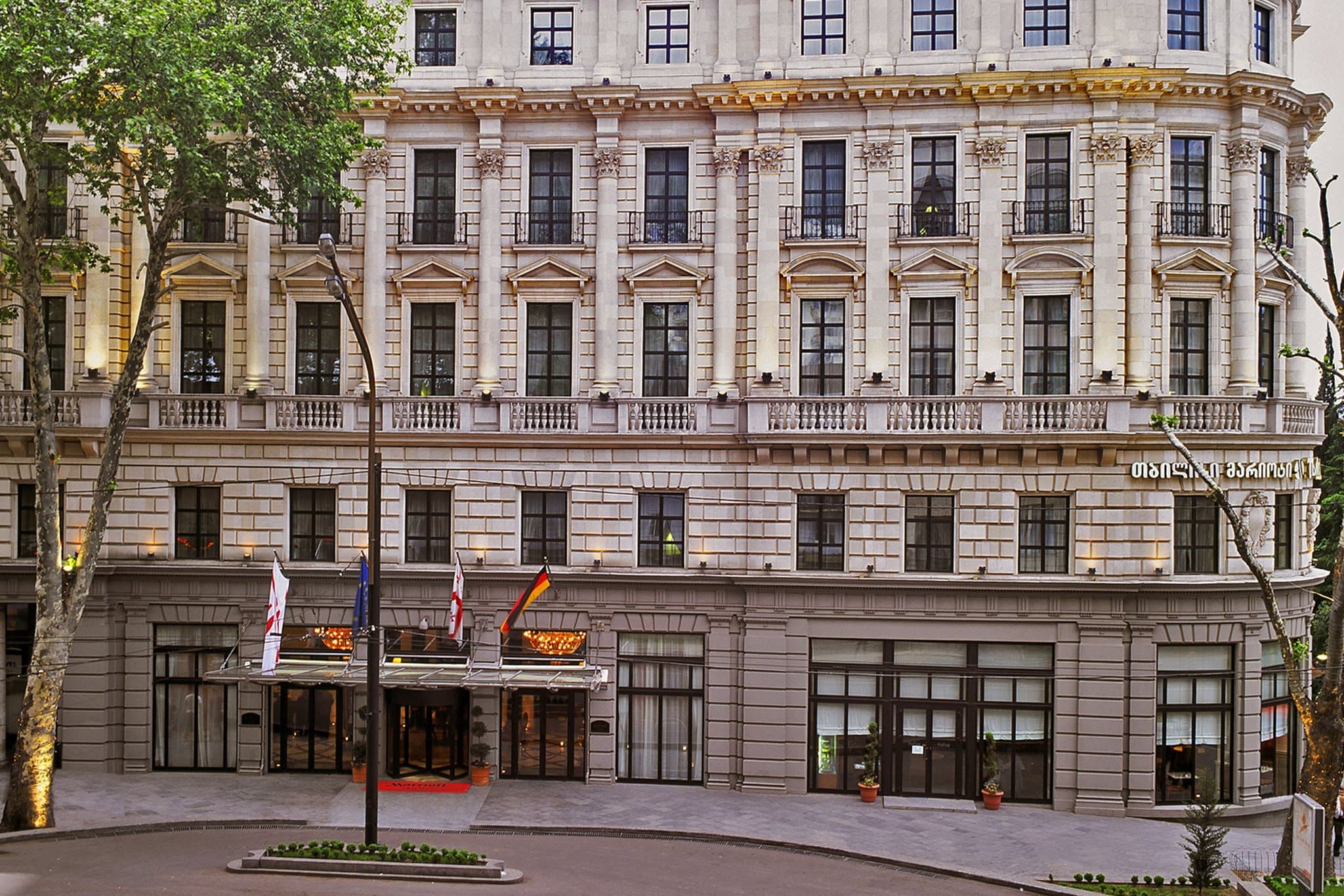The circular 1915 facade of the Tbilisi Marriott Hotel lit up at night on Rustaveli Avenue.