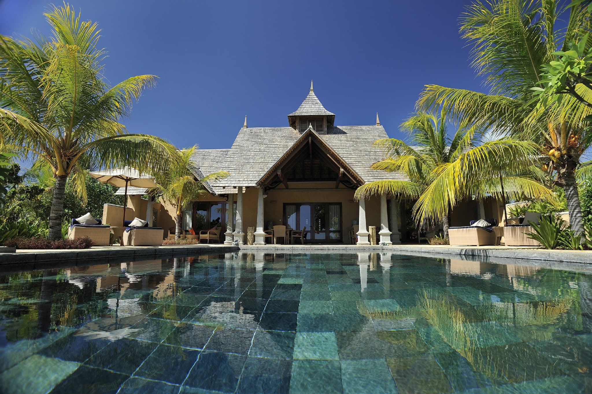 A private infinity pool at Maradiva Villas Resort Mauritius reflecting the thatched villa roof and golden sunset light.