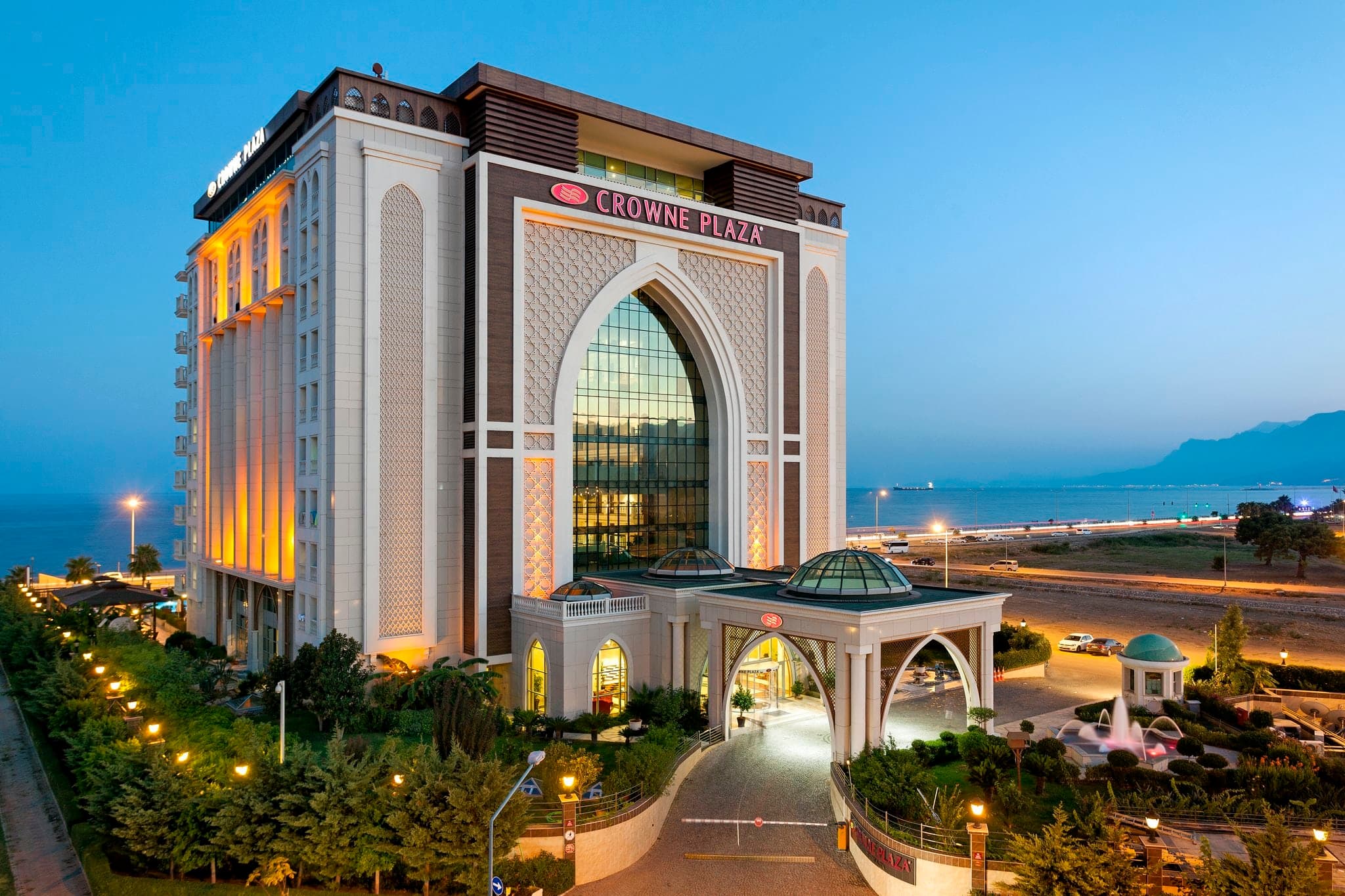 View of the Crowne Plaza Antalya atrium featuring soaring Seljuk-style arches and warm lighting.