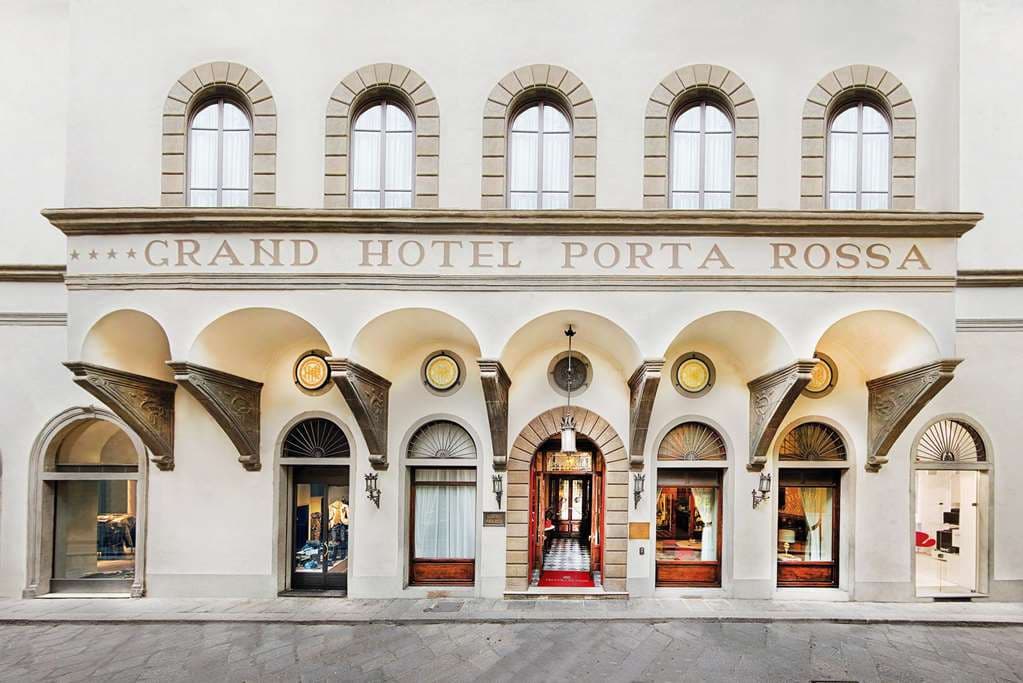 The weathered stone exterior of the 13th-century Torre Monalda rising above the red-tiled rooftops of Florence.