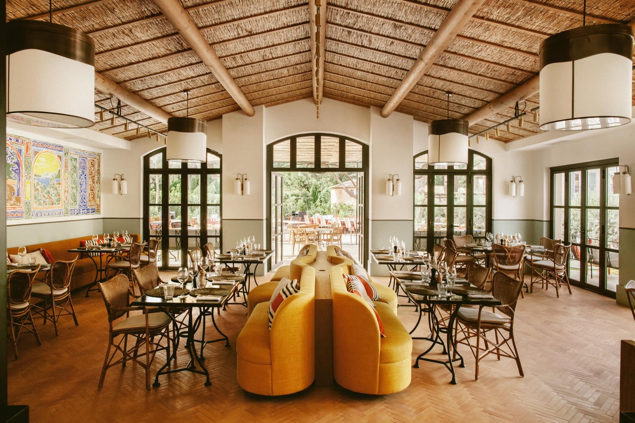 Emerald-tiled swimming pool at Hotel Lou Pinet surrounded by vintage yellow umbrellas and pine trees.