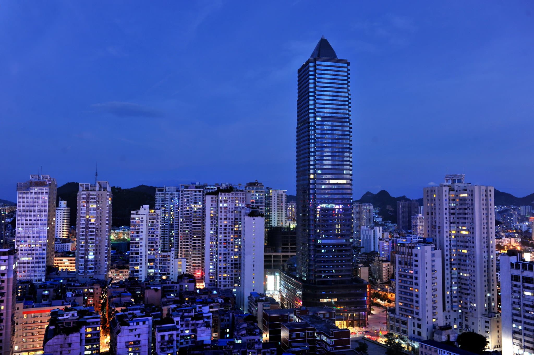 Night view of the Kempinski Hotel Guiyang's 53 Lounge overlooking the illuminated city skyline and distant hills.