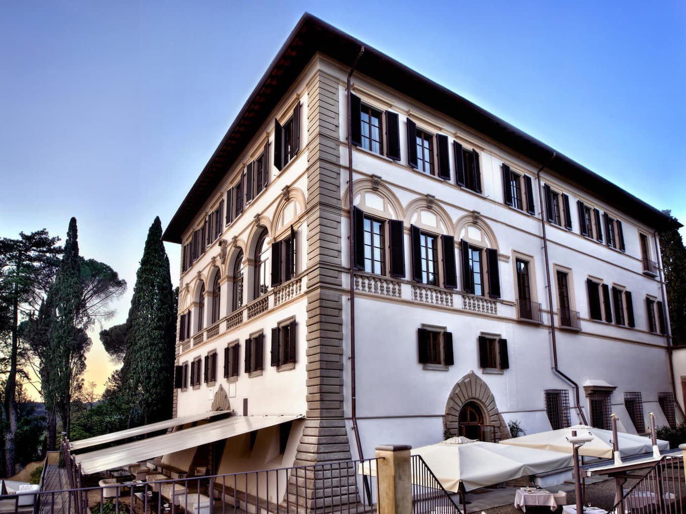 The terrace at Il Salviatino at sunset featuring laid tables and a panoramic view of the Florence Duomo and skyline.