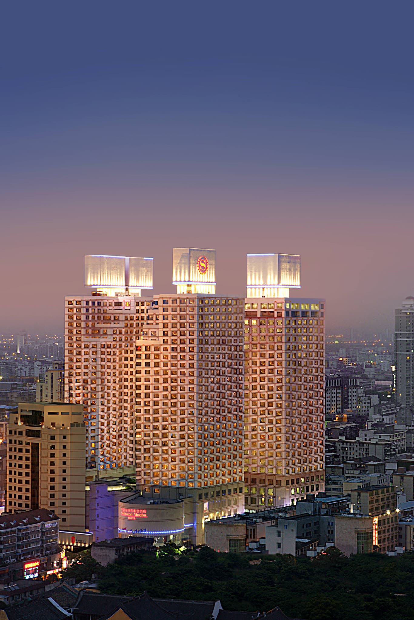 A dramatic view of the Sheraton Ningbo's transparent glass pyramid pool ceiling illuminated at night.