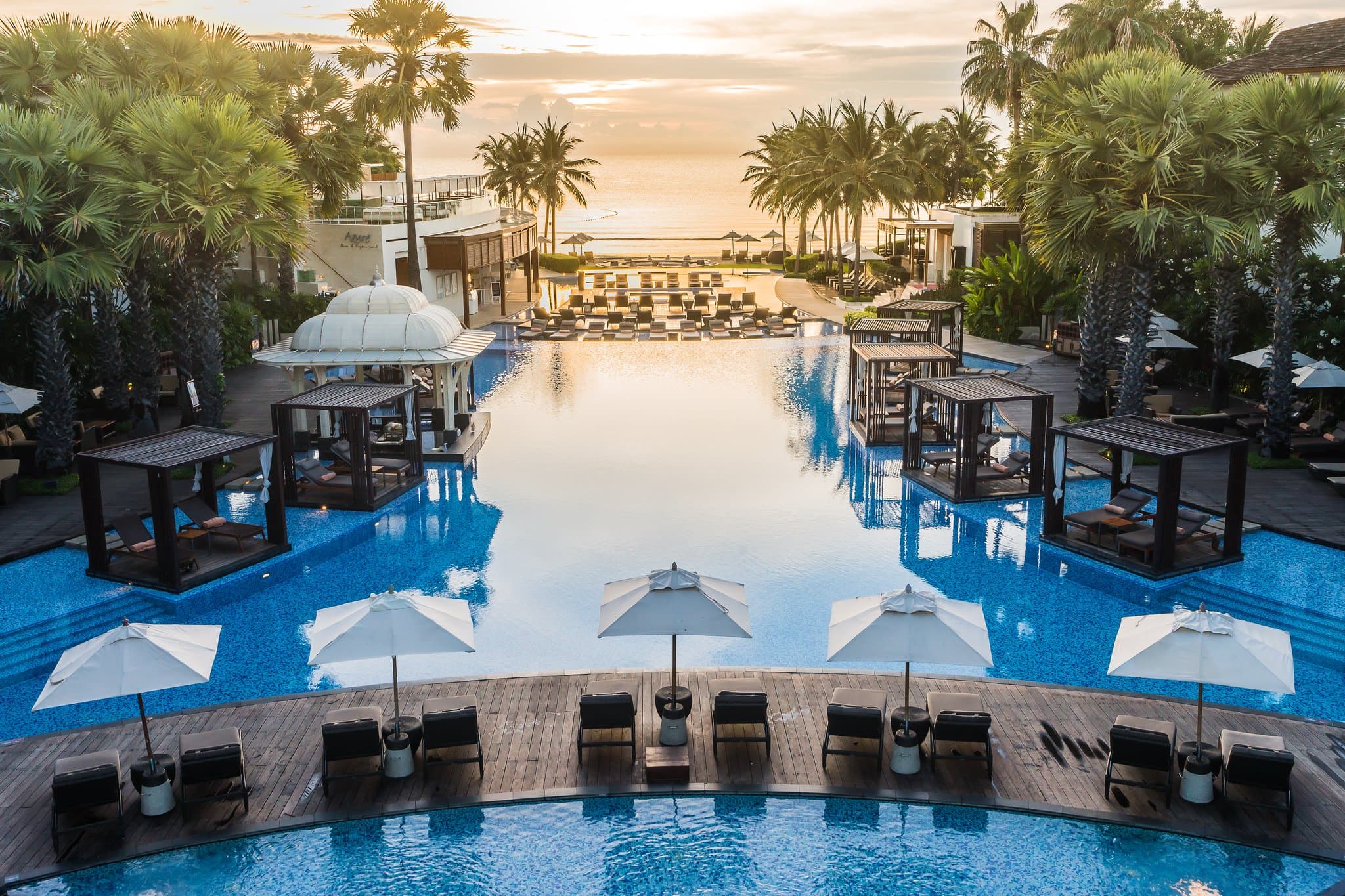 The colonial-style La Residence villa at InterContinental Hua Hin Resort, framed by palm trees and the central lagoon pool.