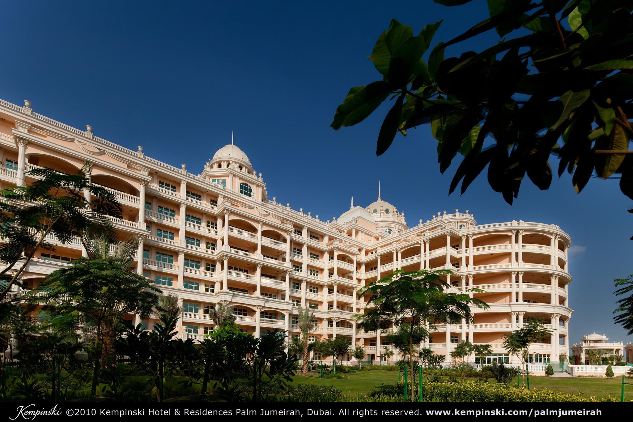 Symmetrical view of Kempinski Palm Jumeirah's main pool leading to the palace facade at twilight.