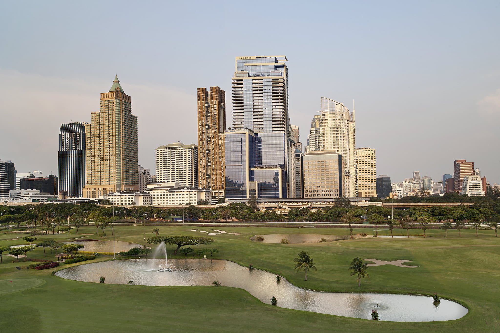 The St. Regis Bangkok 15th-floor infinity pool overlooking the green expanse of the Royal Bangkok Sports Club and city skyline.
