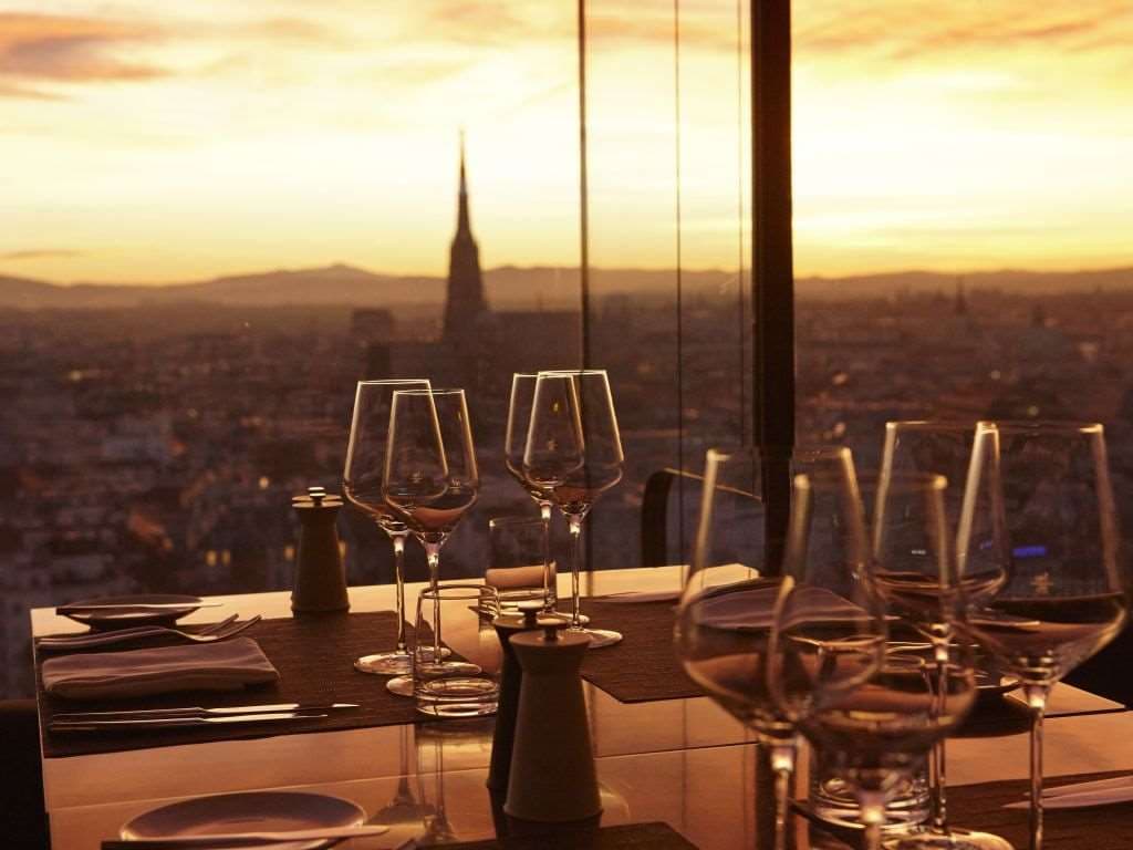 The illuminated multi-colored ceiling art of Das LOFT restaurant on the 18th floor at night, overlooking the Vienna skyline.