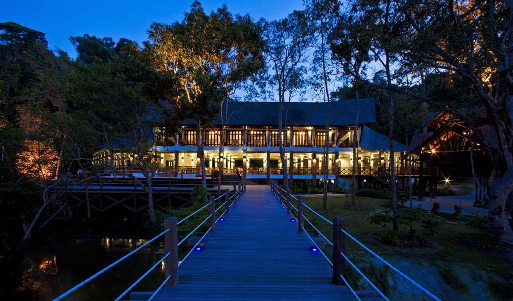 A timber villa at Bungaraya Island Resort nestled in the dense jungle hillside overlooking the turquoise South China Sea.