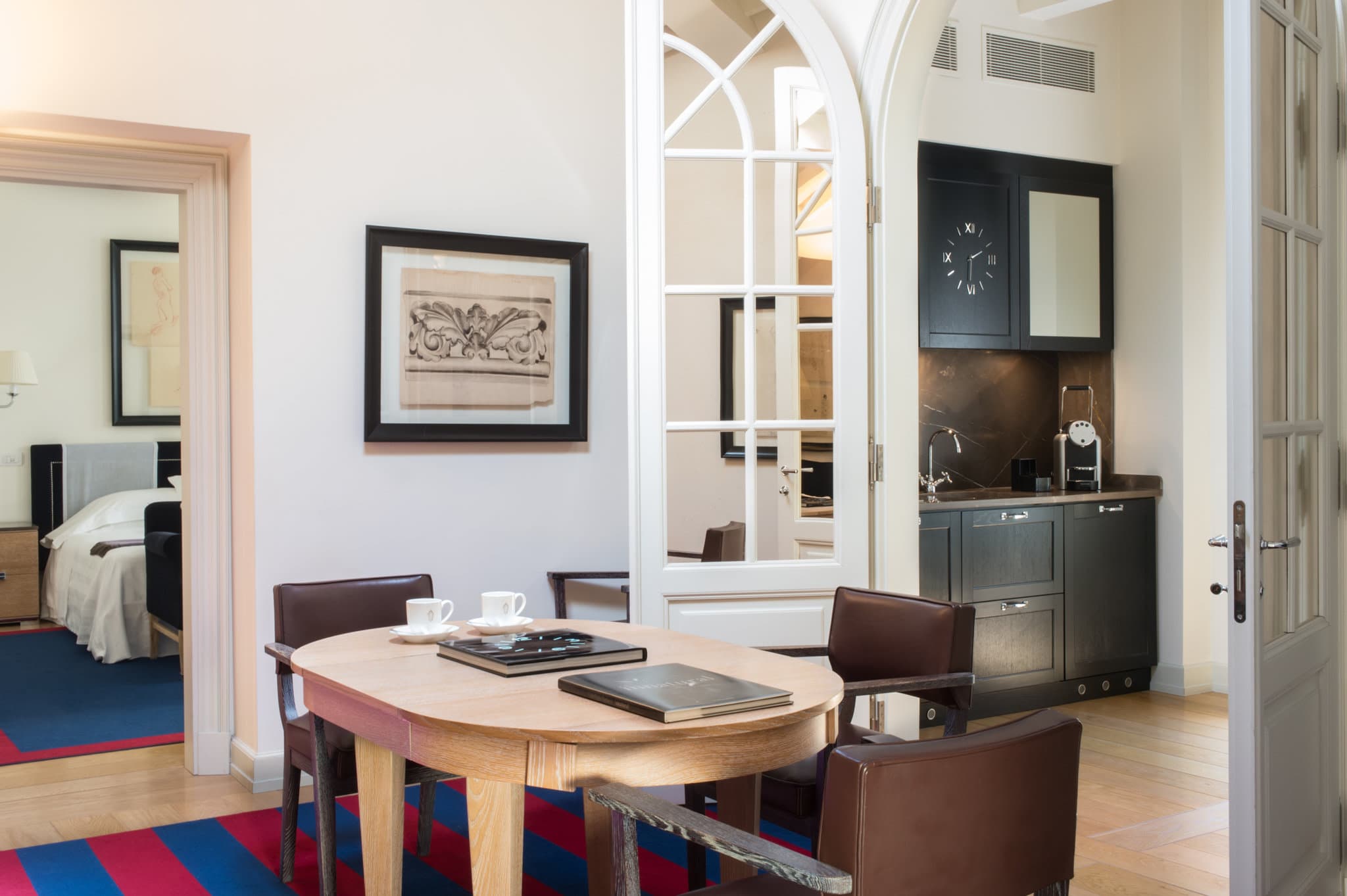 Interior of Palazzo Vecchietti showing a high-ceilinged suite with contemporary grey sofas, curated art, and large windows overlooking Florence streets.