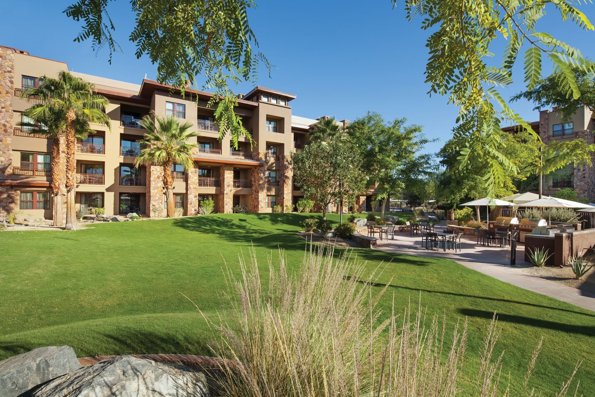 Sun-drenched Mirage Pool deck at Westin Desert Willow Villas with 159-foot water slide and Santa Rosa Mountains in background.
