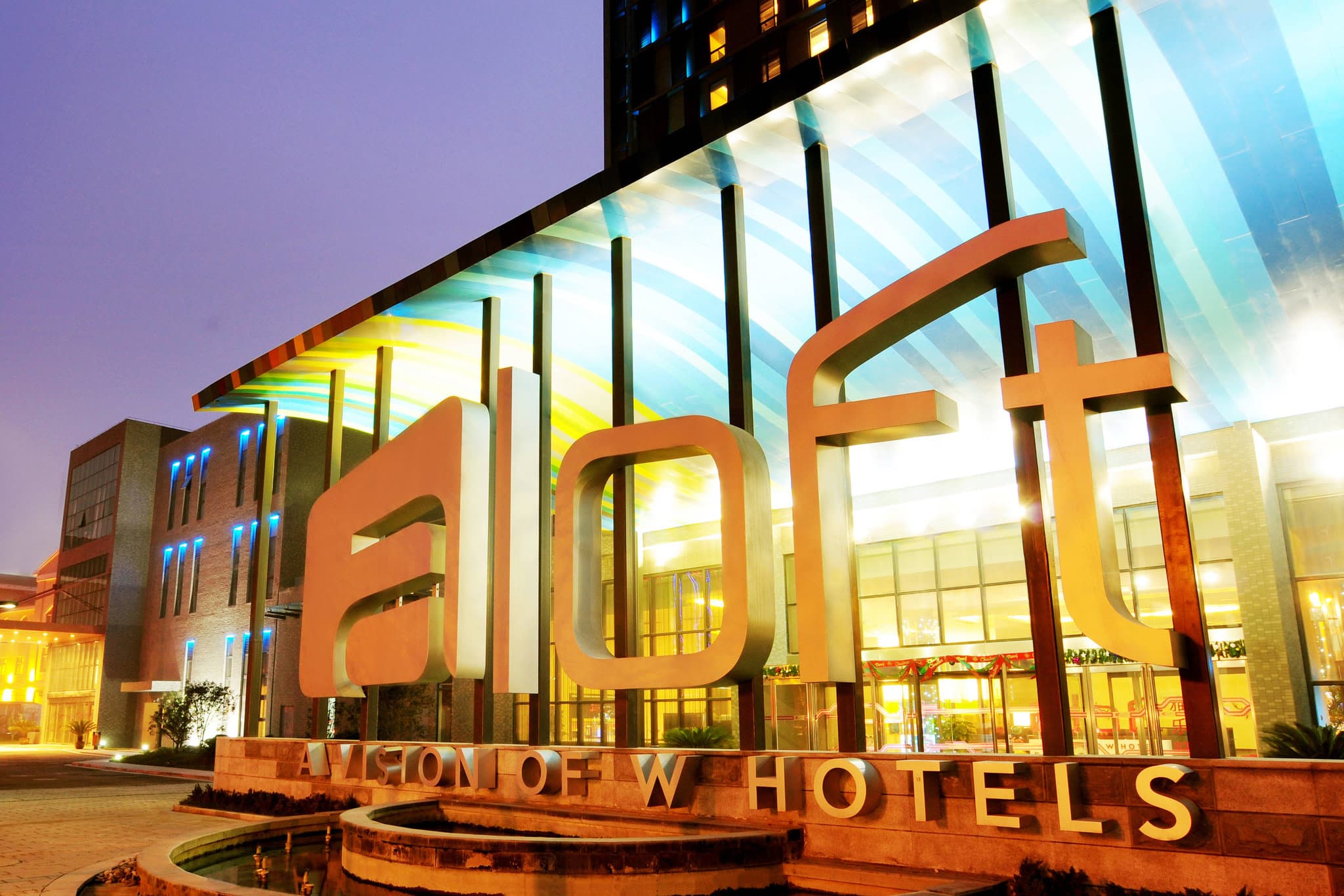 Neon-lit W XYZ Bar at Aloft Zhengzhou Shangjie featuring industrial ceiling pipes and modern lounge seating.