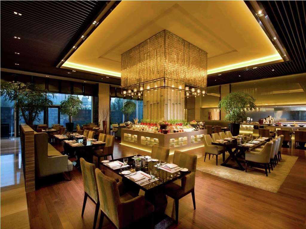 A panoramic view of the Hilton Dalian's Executive Lounge at dusk, overlooking the illuminated Dalian East Harbor.