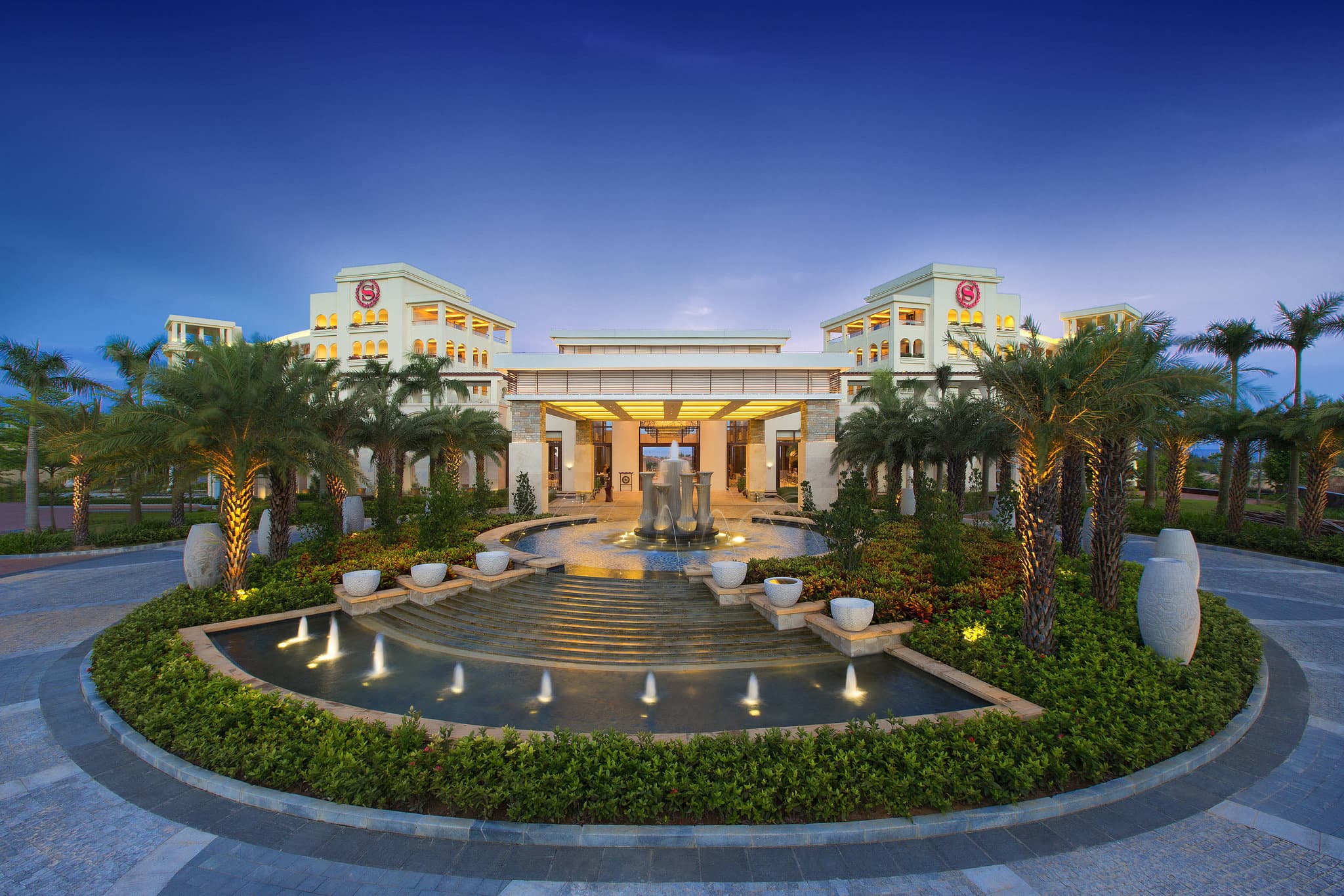 Aerial view of the Sheraton Sanya Haitang Bay Resort's 11-pool complex weaving through tropical gardens near the beach.