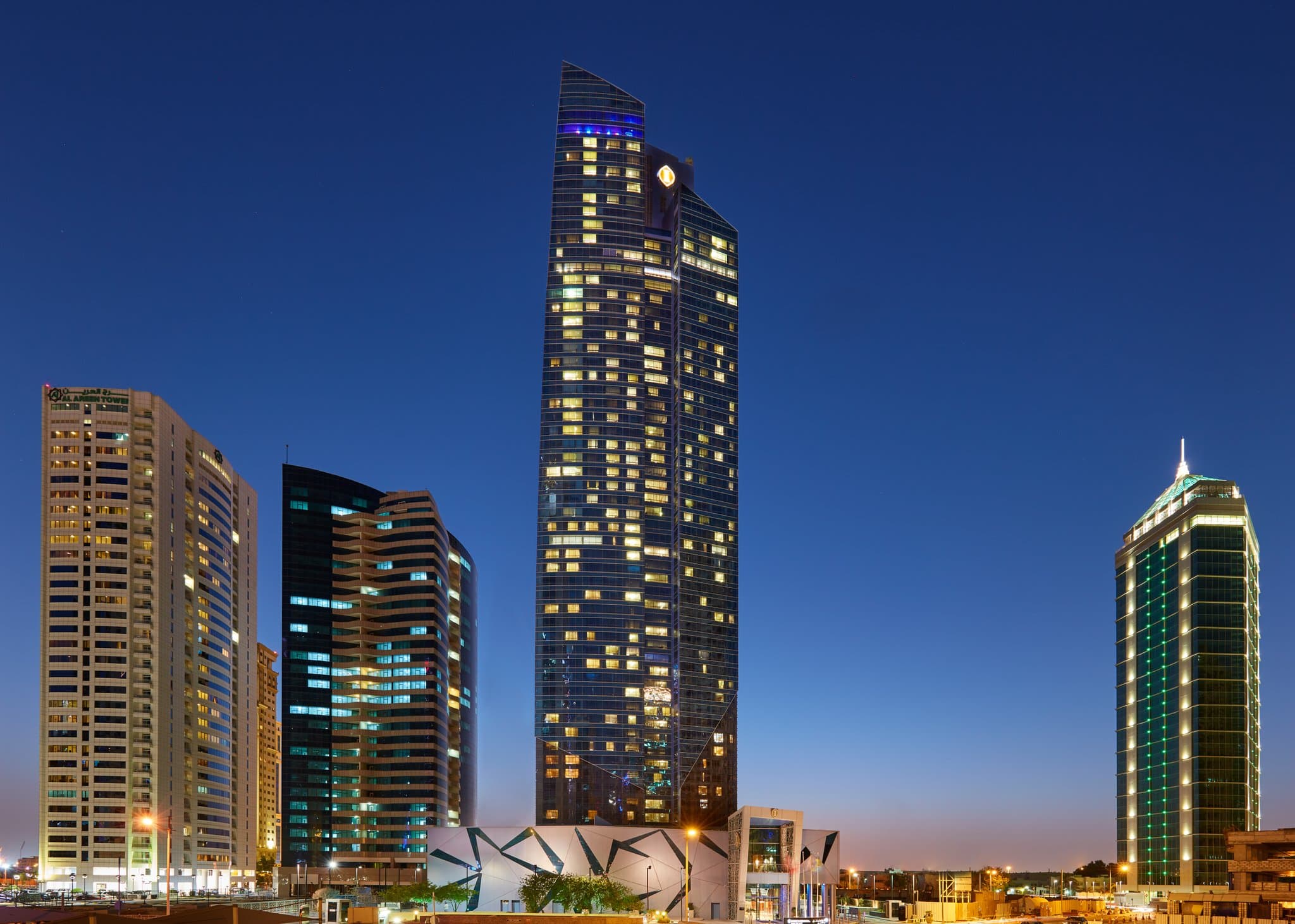 Low-angle night shot of the InterContinental Doha The City tower piercing the West Bay skyline, with the neon violet glow of La Vista 55 visible at the summit.
