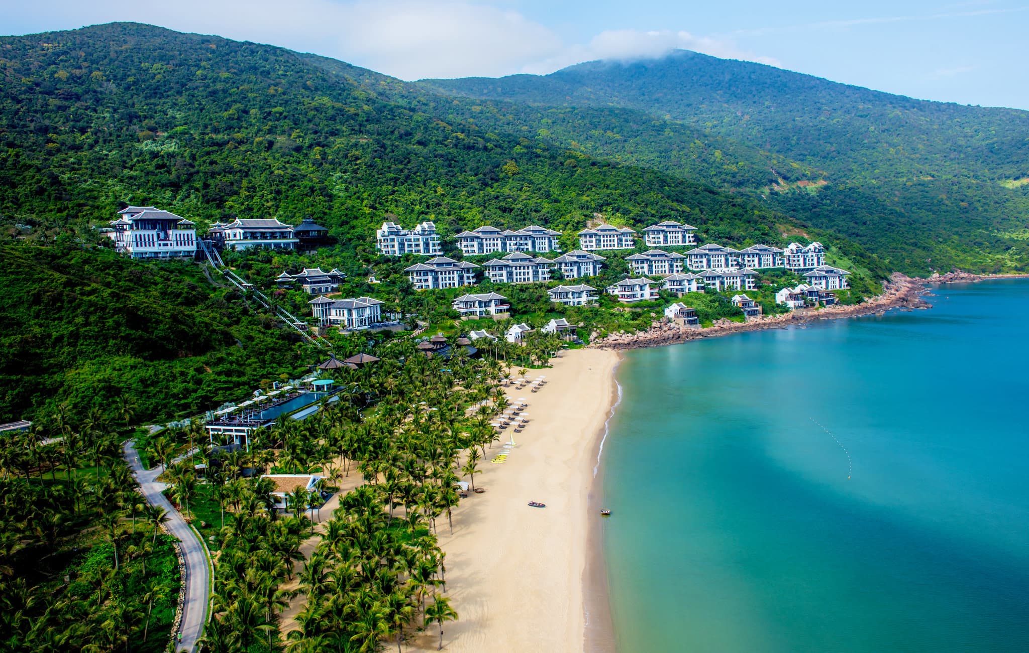 The striking black and white architecture of InterContinental Danang cascading down a lush jungle cliffside, featuring the signature Nam Tram funicular track.