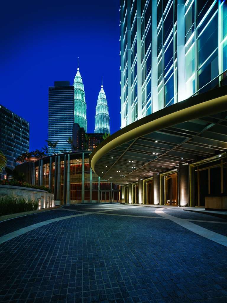 Grand Hyatt Kuala Lumpur free-form swimming pool surrounded by lush tropical palm trees and the glass-enclosed Poolhouse restaurant.