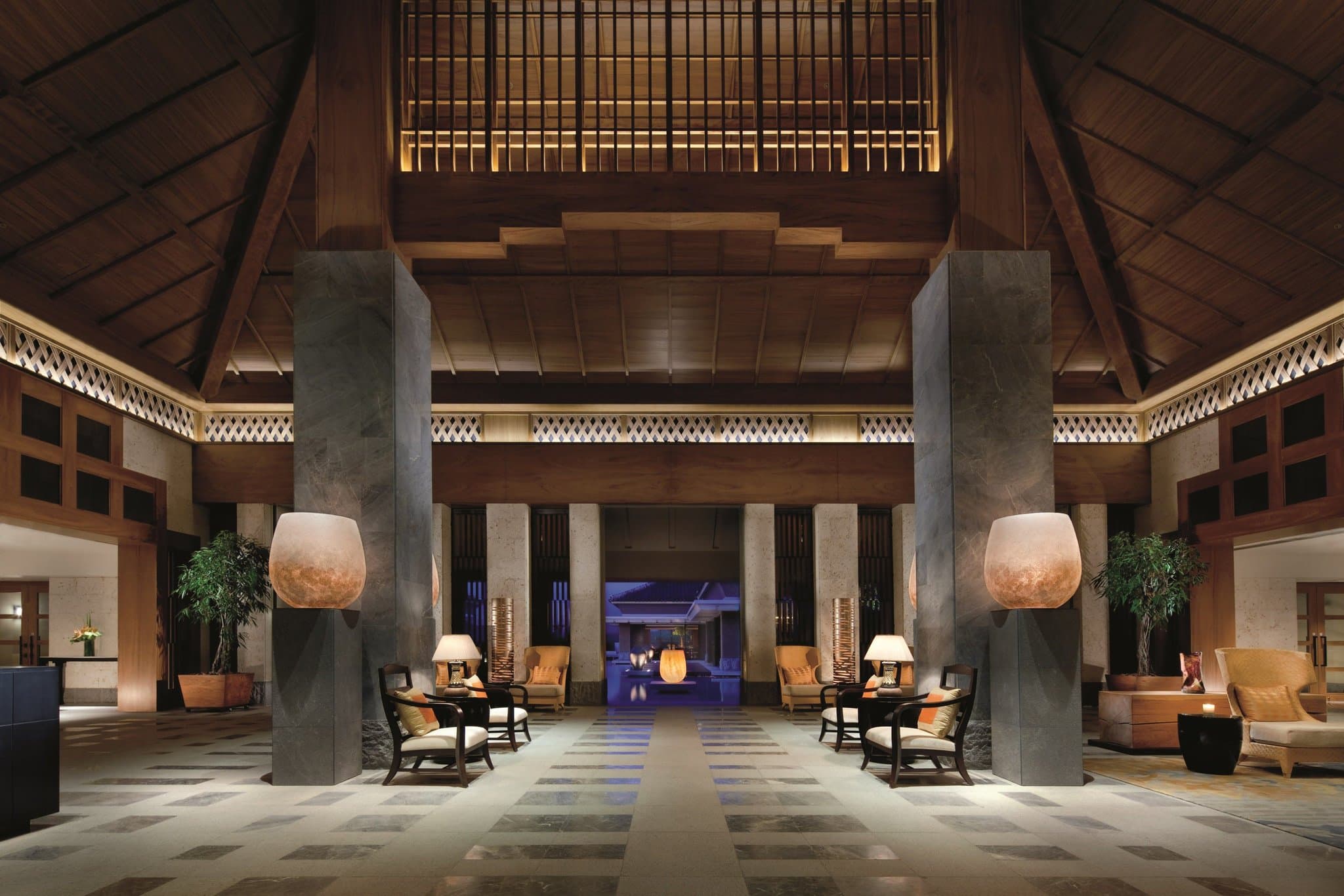 Sunset view of The Ritz-Carlton Okinawa lobby water basin reflecting the golf course and Nago Bay.