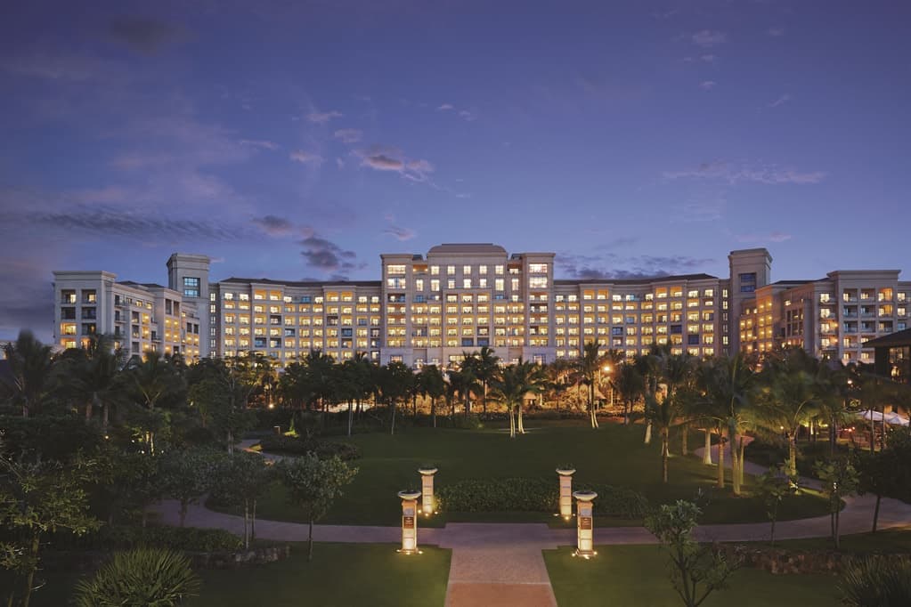 View from Grand Hotel Haikou balcony overlooking the Qiongzhou Strait and tropical gardens at sunset.