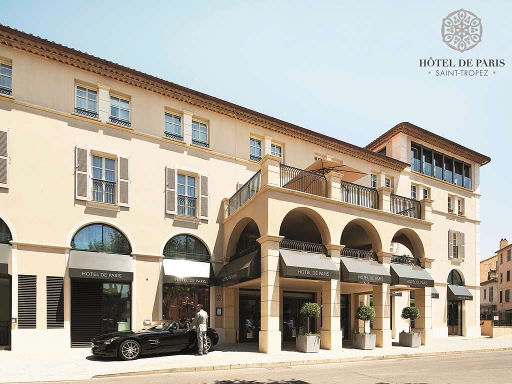 Low-angle view of the suspended glass-bottom pool visible from the Hôtel de Paris Saint-Tropez lobby atrium, featuring modern architectural lines.