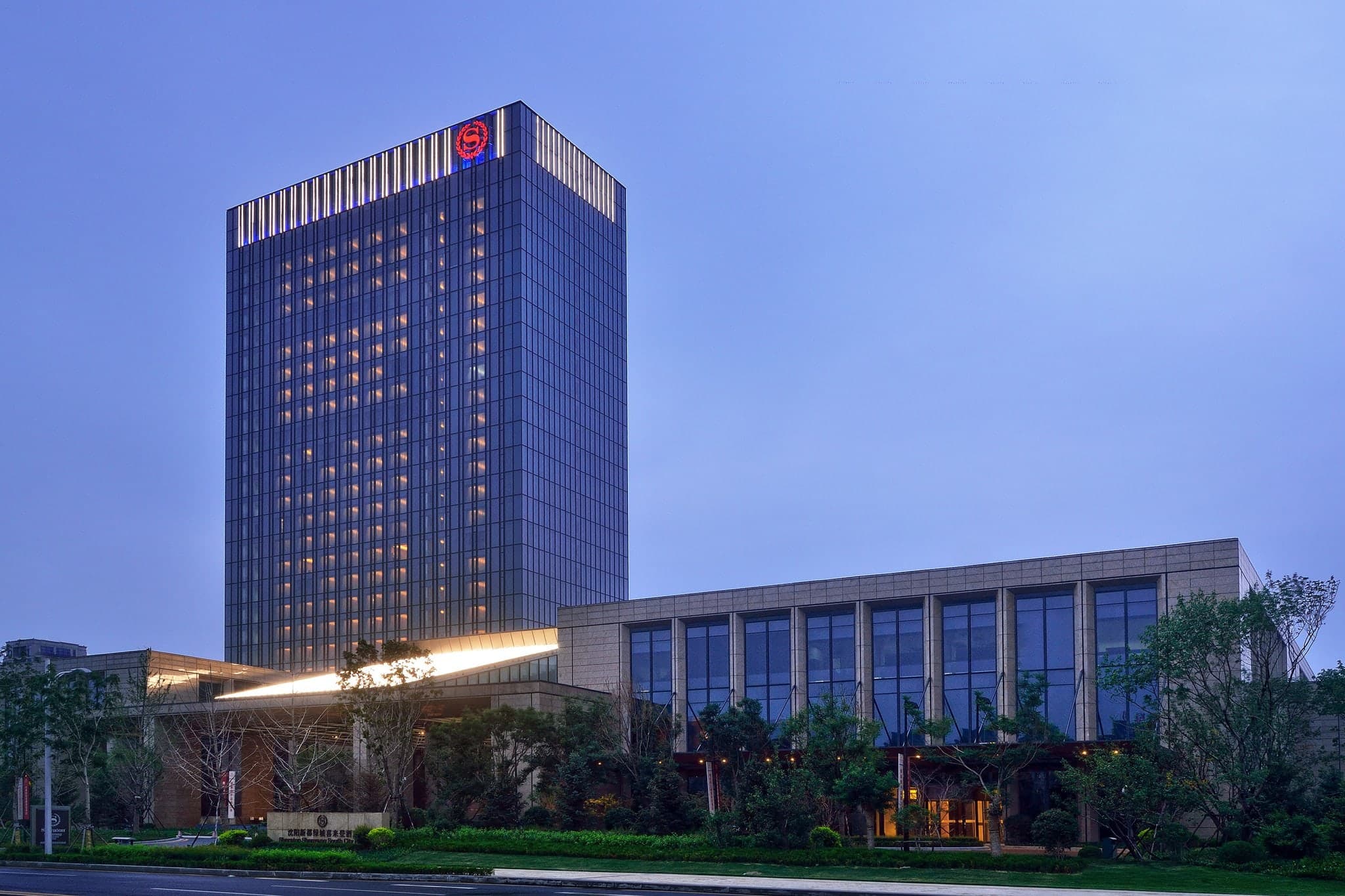 Sheraton Shenyang South City lobby featuring a grand central chandelier and vertical architectural lines, evoking a modern corporate cathedral.