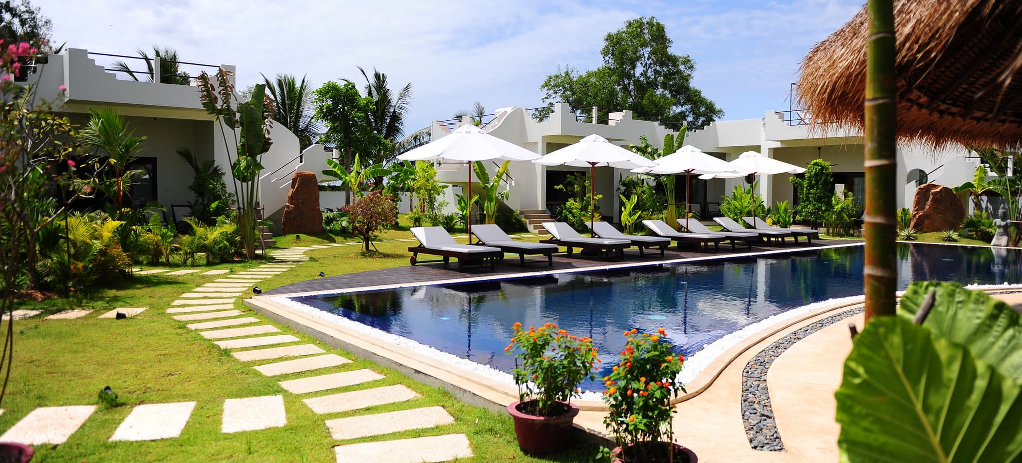 Whitewashed Mediterranean-style villas at Navutu Dreams Siem Reap reflecting in the saltwater lagoon pool surrounded by tropical sugar palms.