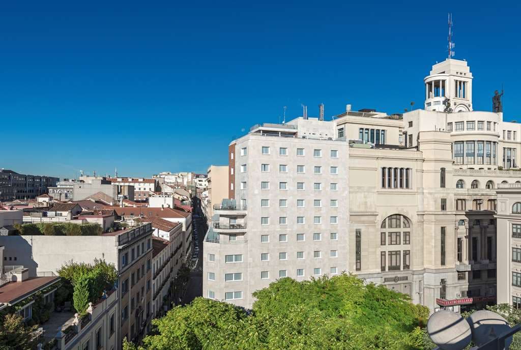 Panoramic twilight view from Ático Casa Suecia rooftop terrace overlooking the Metropolis building and Madrid skyline.