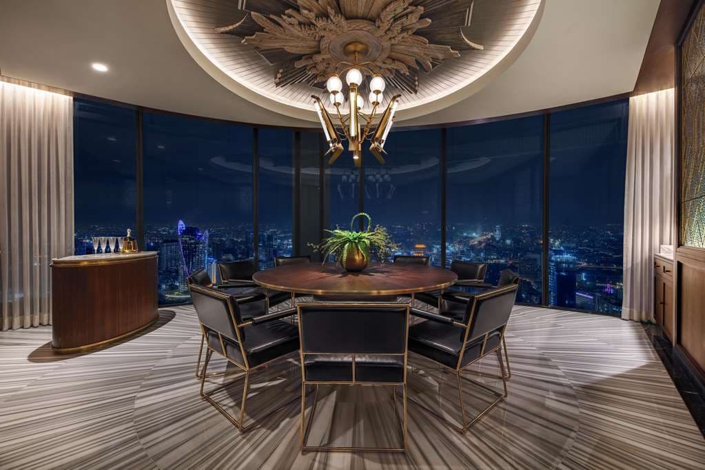 The Waldorf Astoria Bangkok's curved infinity pool on the 16th floor, featuring a floating magnolia petal canopy and overlooking the green Royal Bangkok Sports Club and city skyline.