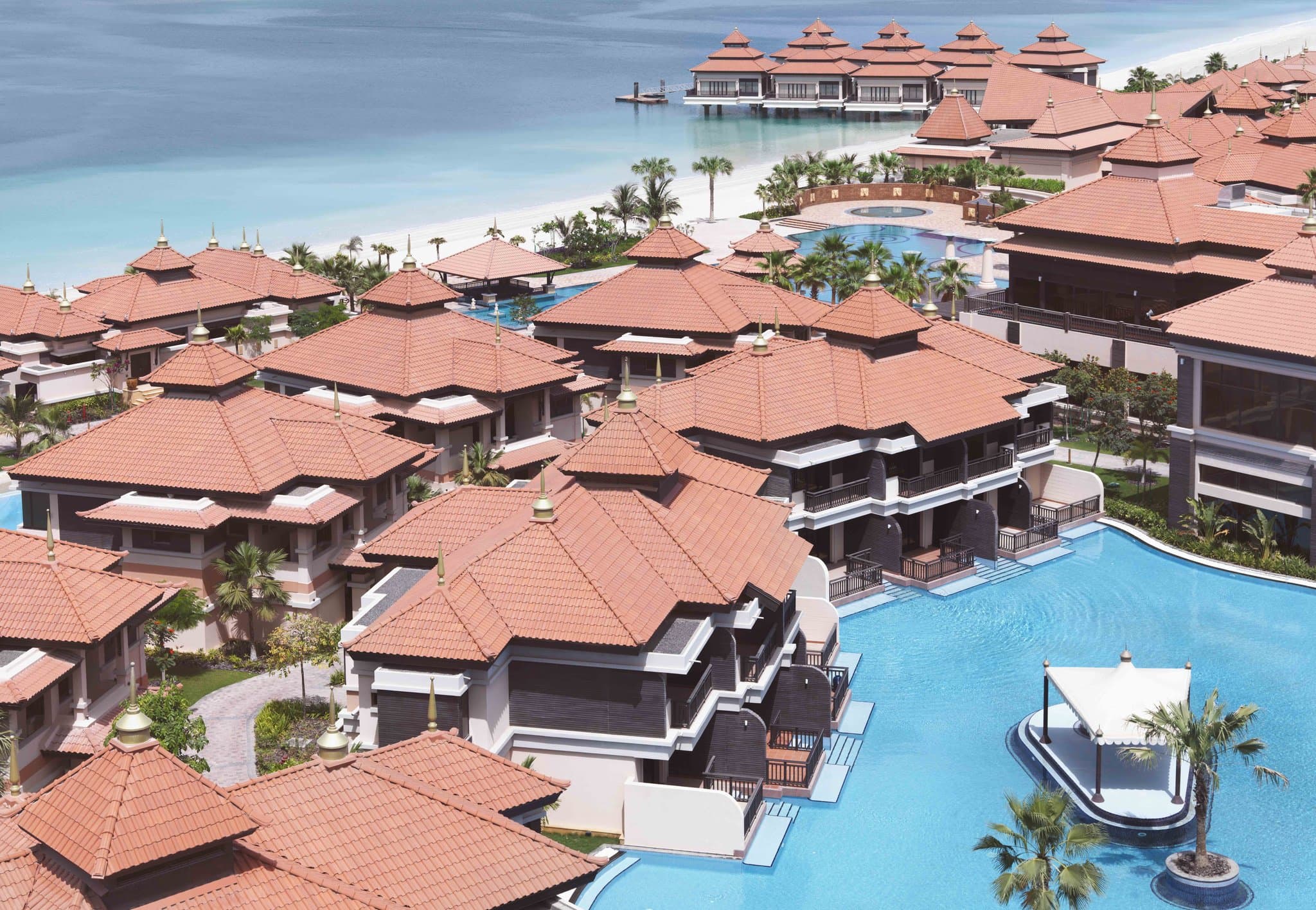 View of the Anantara The Palm lagoon pools winding around Thai-style villas at dusk.