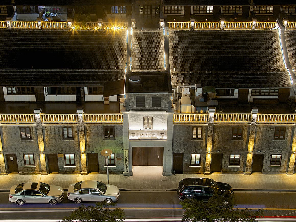 A moody, lantern-lit stone alleyway at Chaptel Hangzhou featuring traditional Shikumen brickwork and arched entryways.