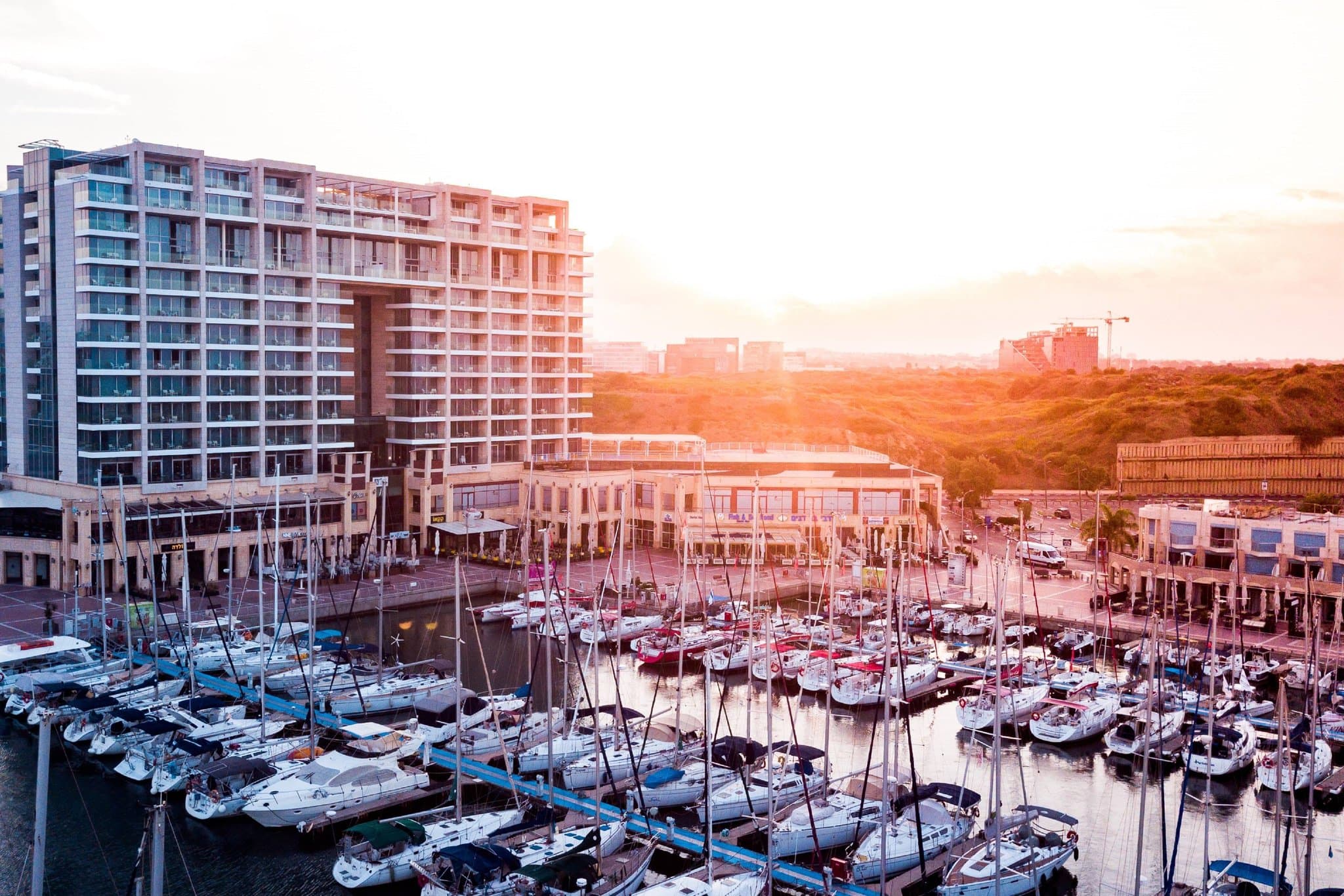 Rooftop infinity pool at The Ritz-Carlton Herzliya at sunset overlooking the Mediterranean Sea and marina yachts.