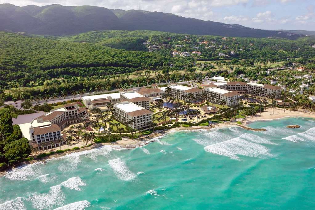 A couple relaxing in a swim-up suite pool at Hyatt Zilara Rose Hall with colonial architecture in the background.