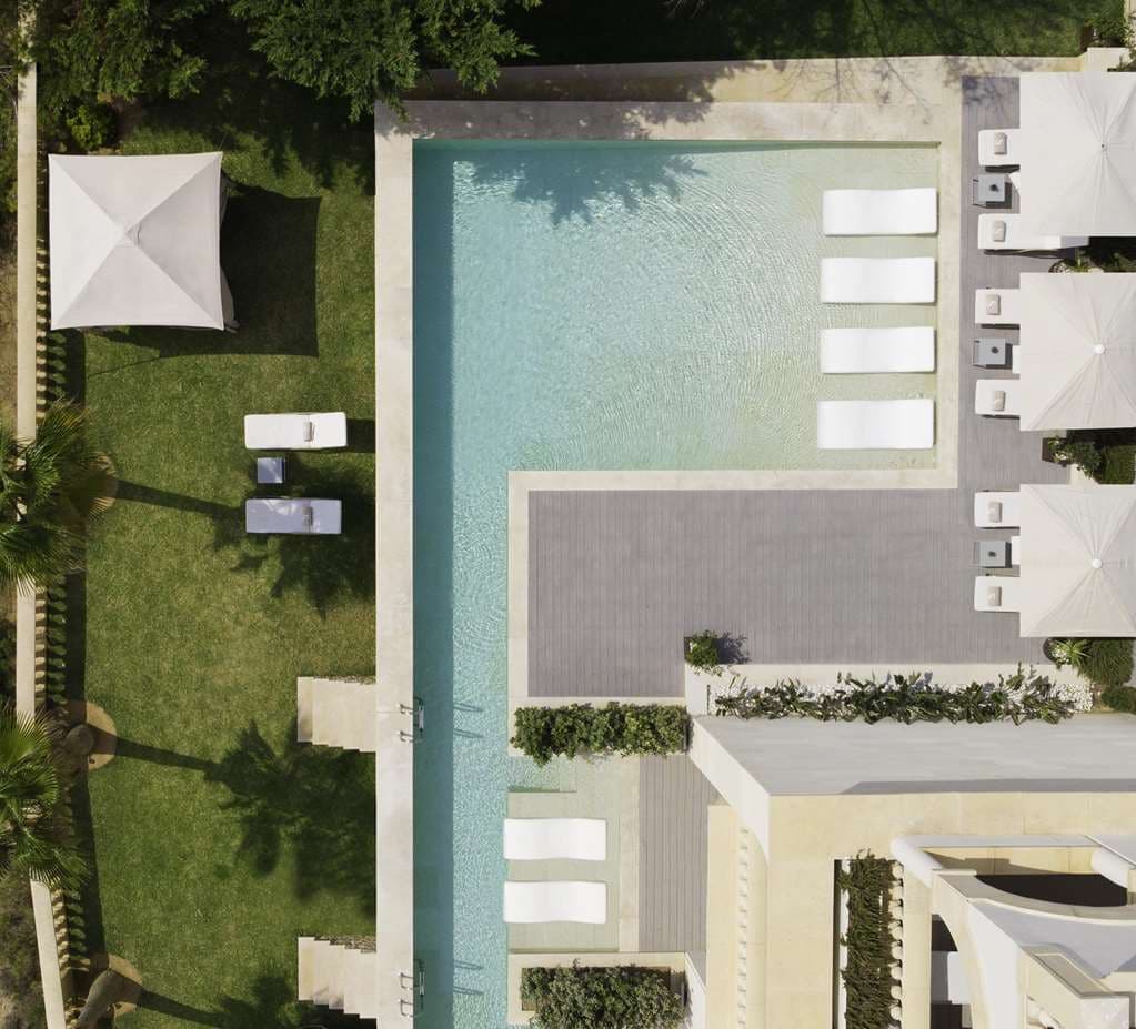 A guest swimming in the private river-pool of a Renaissance Suite at Pure Salt Port Adriano, with the Philippe Starck marina and deep blue Mediterranean sea in the background.