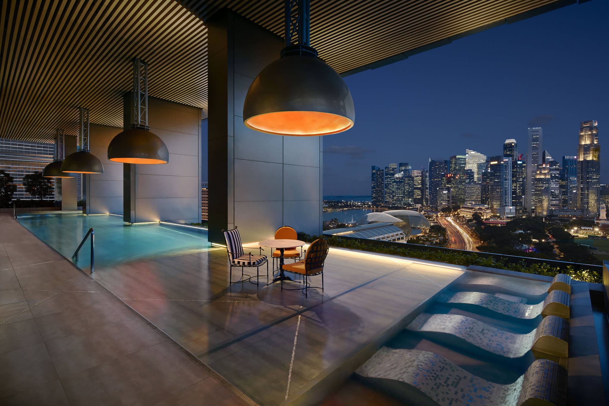 A guest relaxing in the Flow18 infinity pool at JW Marriott Singapore South Beach, overlooking the Marina Bay skyline and F1 track.