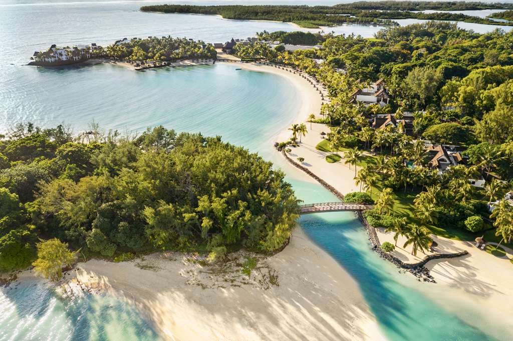 Aerial view of Shangri-La Le Touessrok showing the wooden bridge connecting to the Frangipani islet, surrounded by turquoise Mauritian waters.