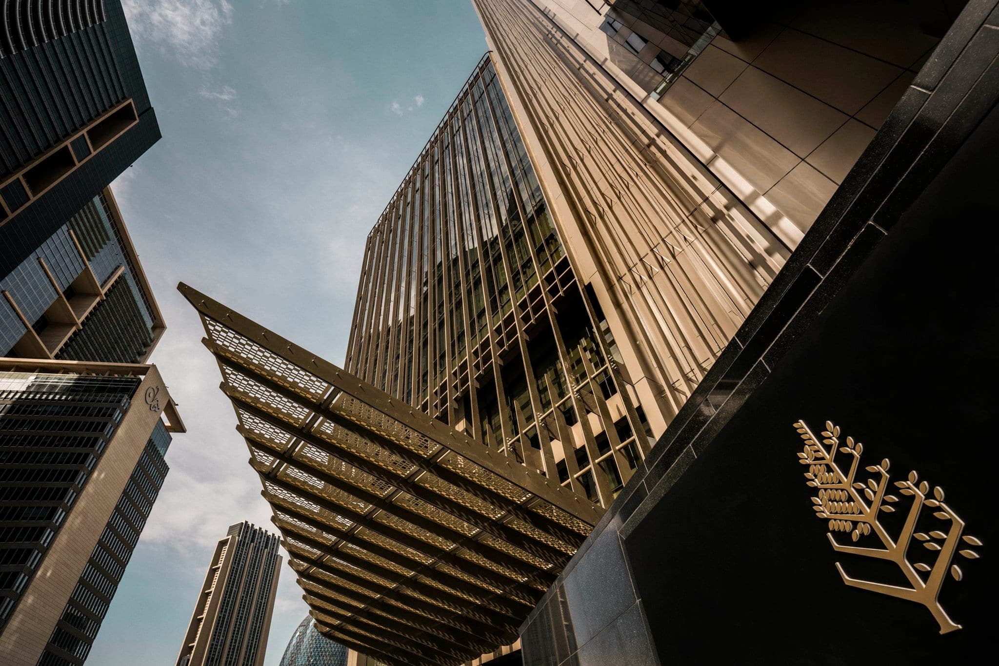 A swimmer visible through the transparent glass walls of the rooftop pool at Four Seasons DIFC, with the Dubai skyline in the background.