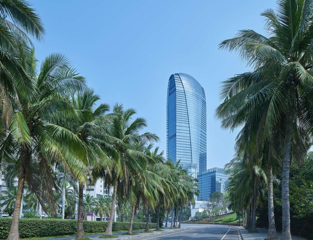 Hilton Haikou skyscraper illuminated at night, towering over Haikou Bay with the Century Bridge in the background.
