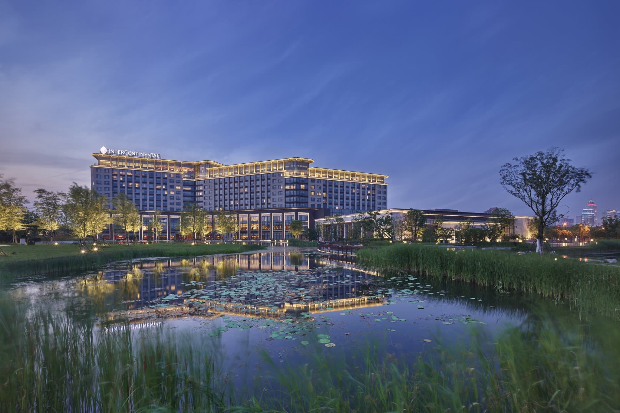 View from InterContinental Nantong room featuring floor-to-ceiling windows overlooking the Yangtze River and lush hotel gardens.