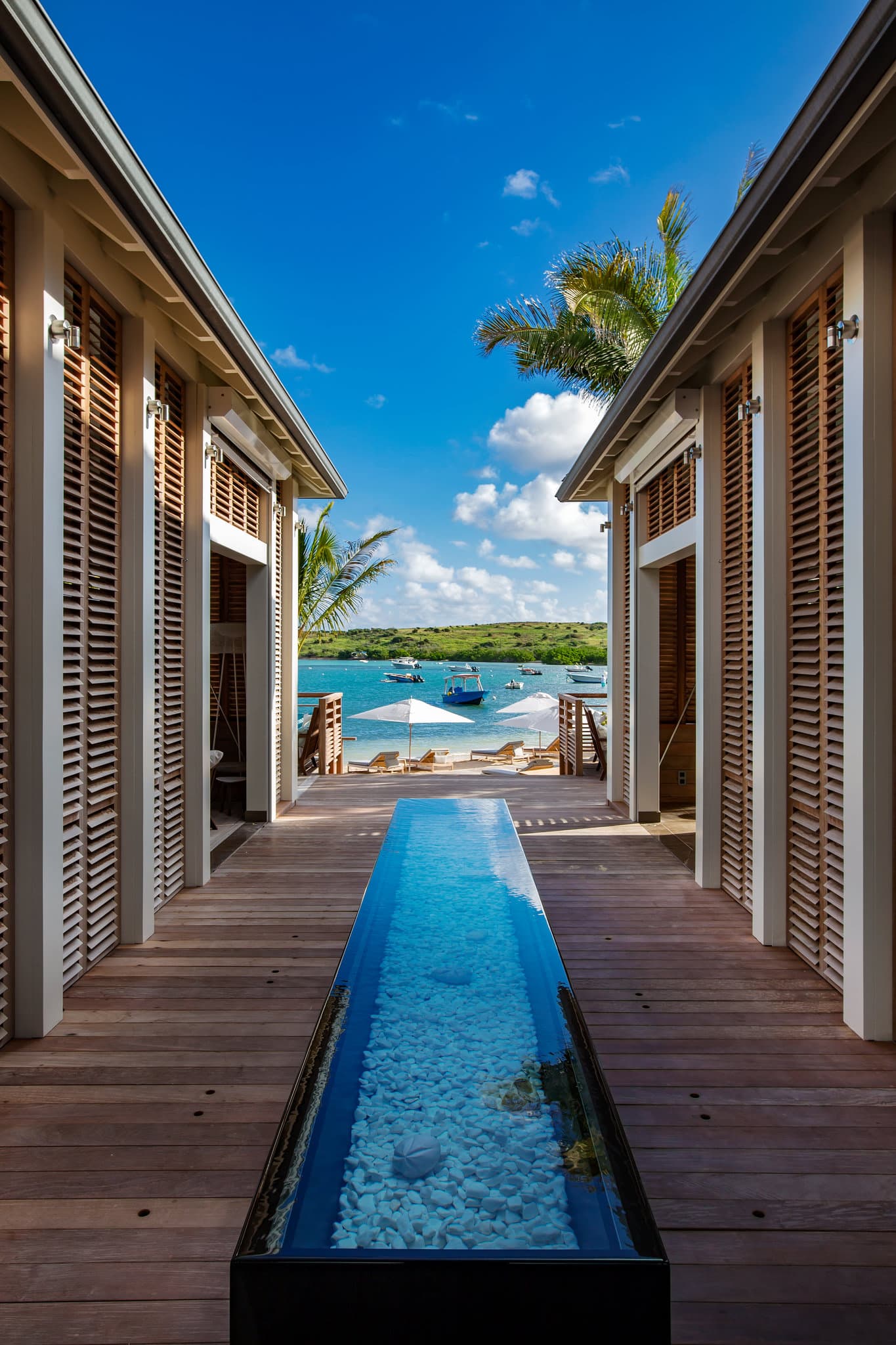 Le Barthélemy Hotel infinity pool overlooking Grand Cul-de-Sac lagoon with palm trees and lounge chairs.