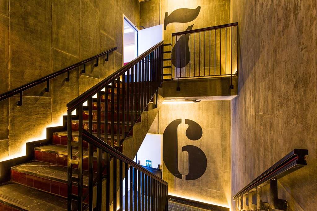 The industrial-chic lobby of Only YOU Hotel Atocha featuring high bookshelves, leather seating, and warm ambient lighting by Lázaro Rosa-Violán.