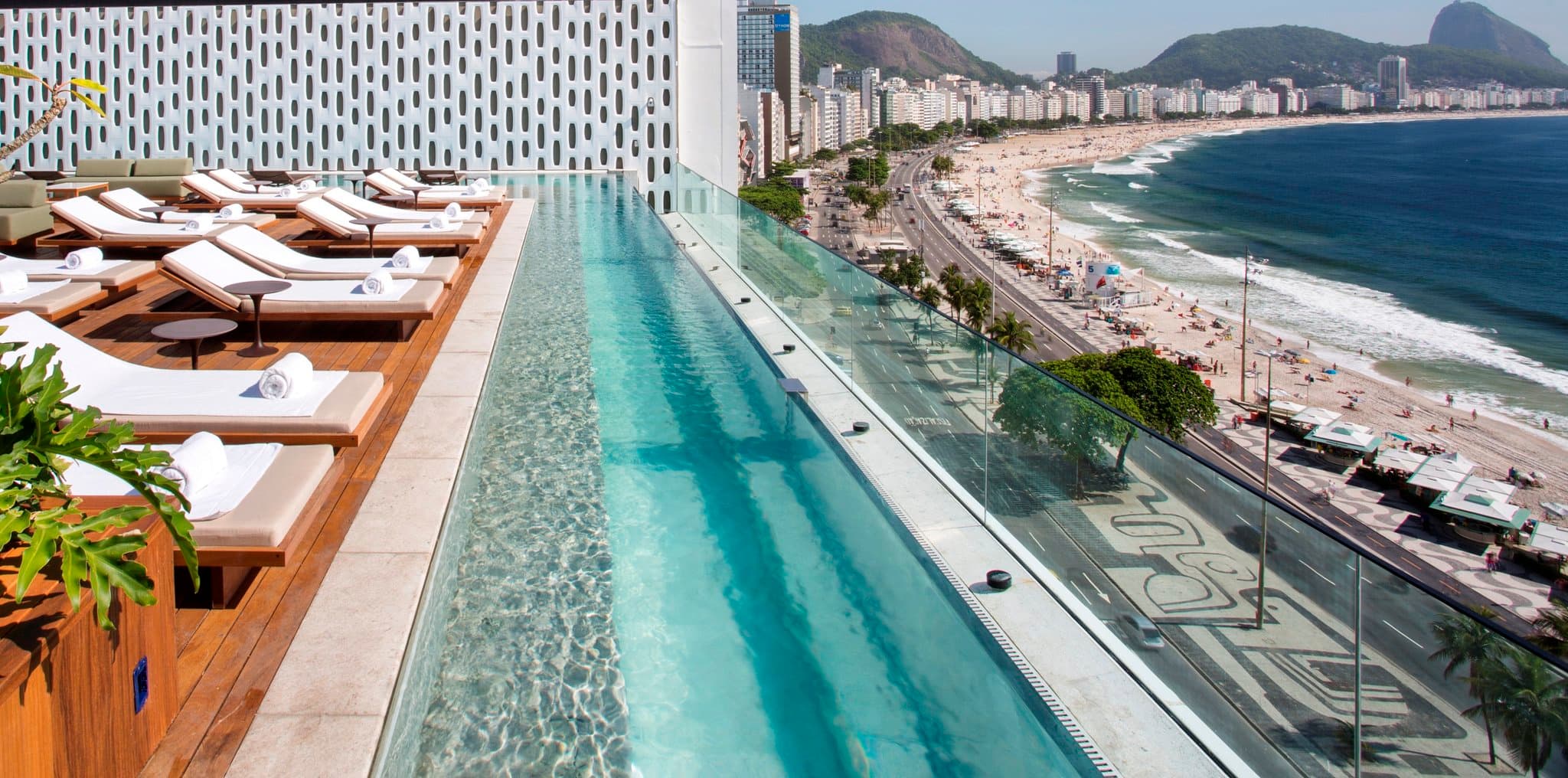 The striking white cobogó façade of Emiliano Rio hotel contrasting with the blue sky and Copacabana beach promenade.